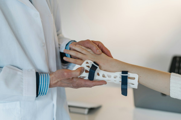 A doctor placing a white plastic brace on a patient's wrist.